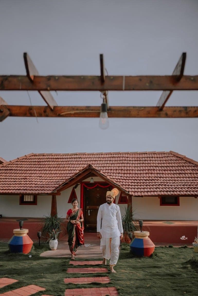 A couple in traditional dress walking the path from the tiled cottage
