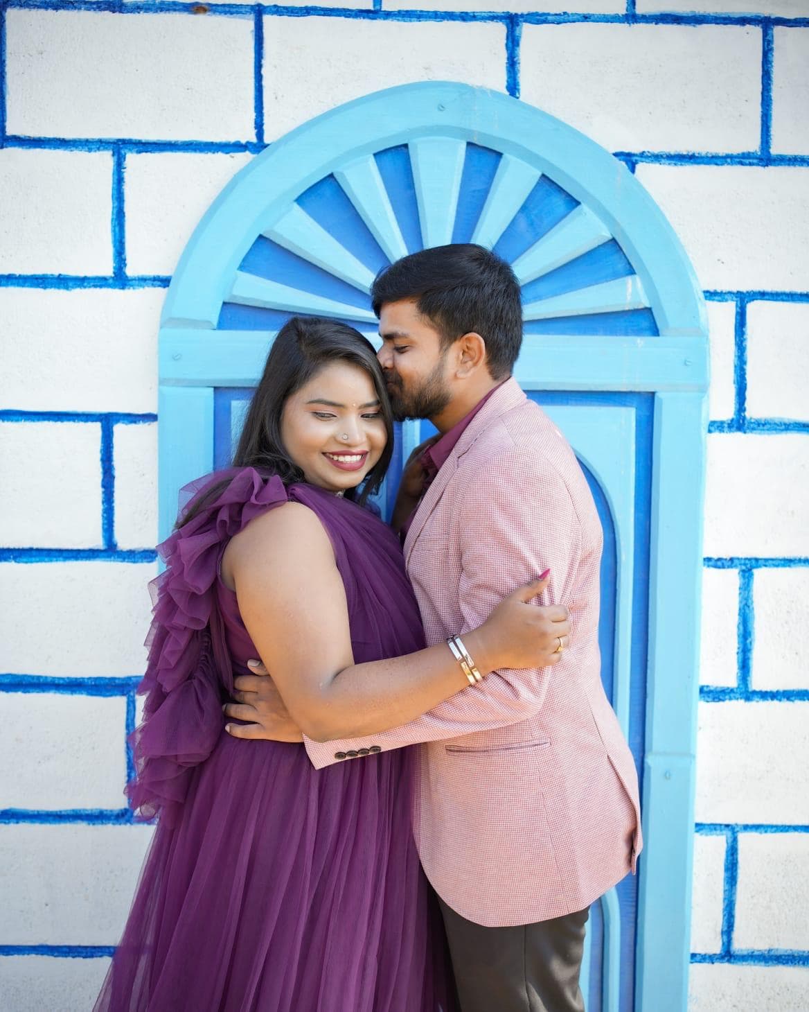 A couple embracing before the blue arched door